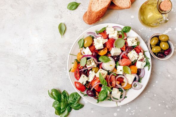 a large portion of appetizing Greek salad with feta cheese, fresh tomatoes, basil, onion olives and olive oil, healthy food.