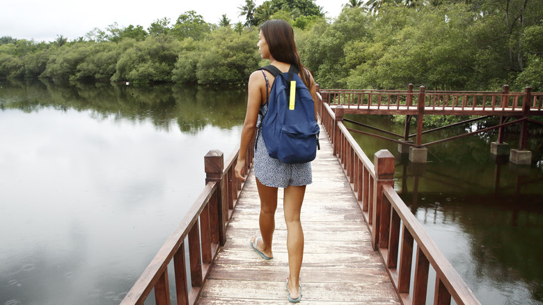 a woman with a backpack crossing a footbridge